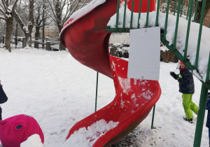 Dziewczynka rzuca śnieżką do celu.